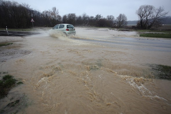 Autó halad a vízátfolyásban a 74-es főúton, a Zala megyei Magyarszerdahelynél. A belvíz több helyen okoz gondot a közlekedésben.