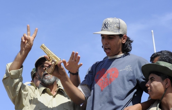 A líbiai felkelők a megölt Kadhafi arany pisztolyával ünnepelnek