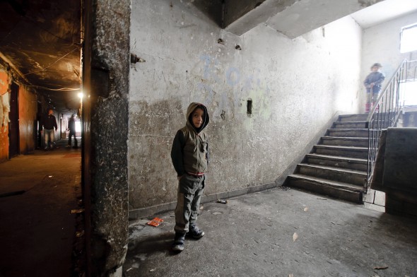 Egy kisfiú áll a fallal elkerített Horea utcai lakóházak egyikének lépcsőházában, Nagybányán. Az önkormányzat tervei szerint még idén felszámolják a városszéli Craica nevű roma nyomornegyed viskóit.