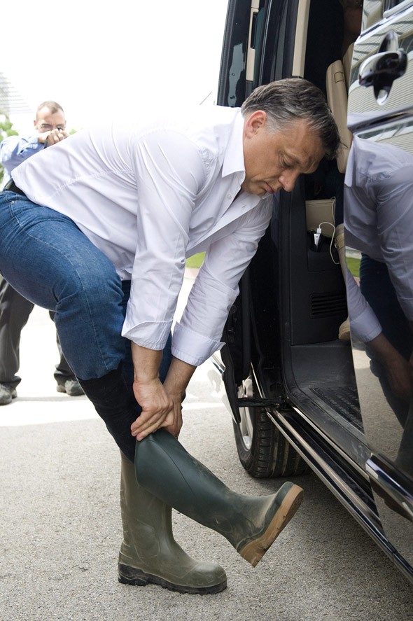 Orbán Viktor miniszterelnök csizmát húz, mielőtt elindul megnézni az árvízi védekezést